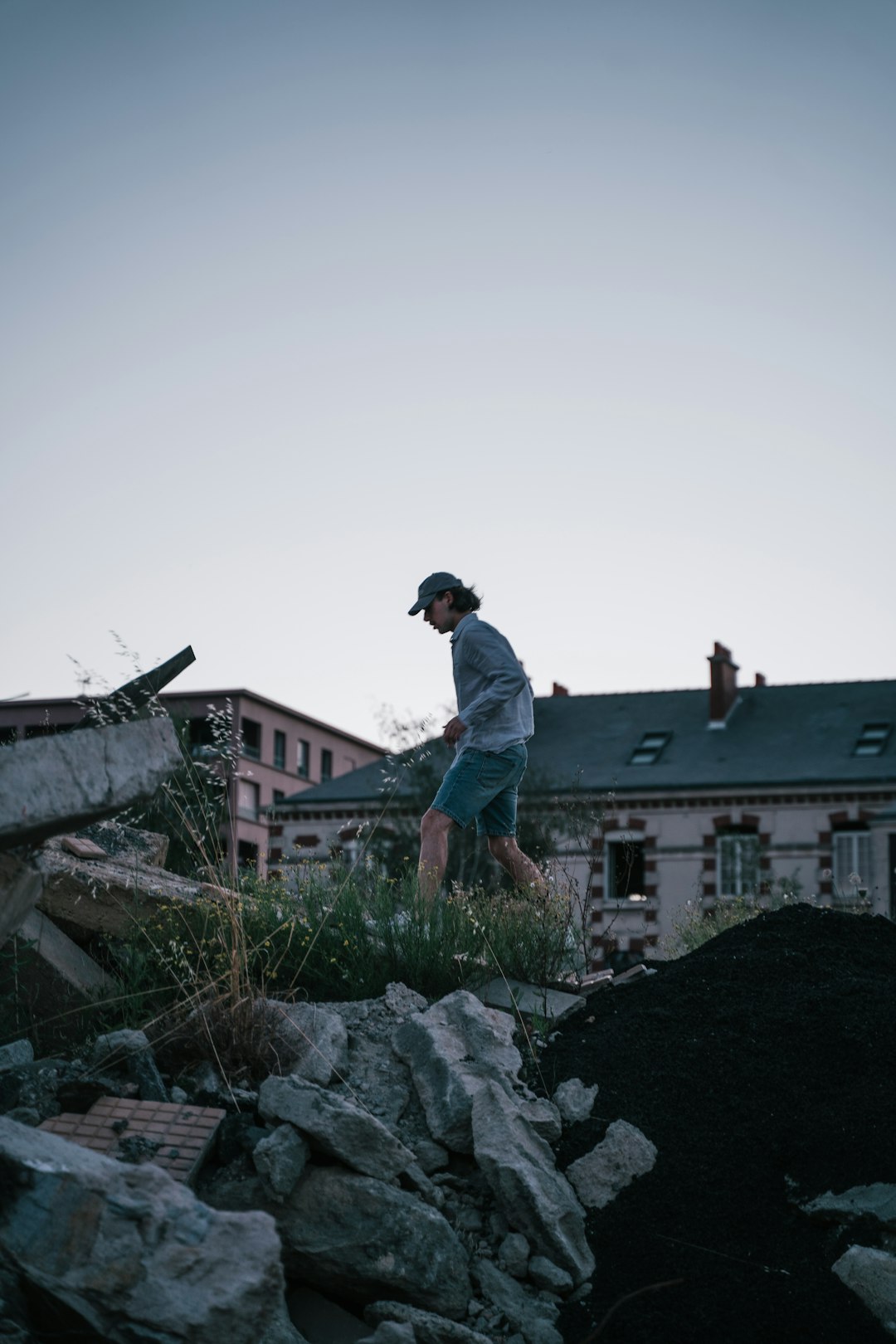 a man standing on a pile of rocks in front of a house