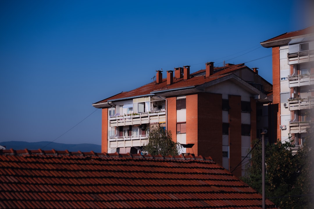 Red brick apartment buildings with tiled roofs under a clear blue sky