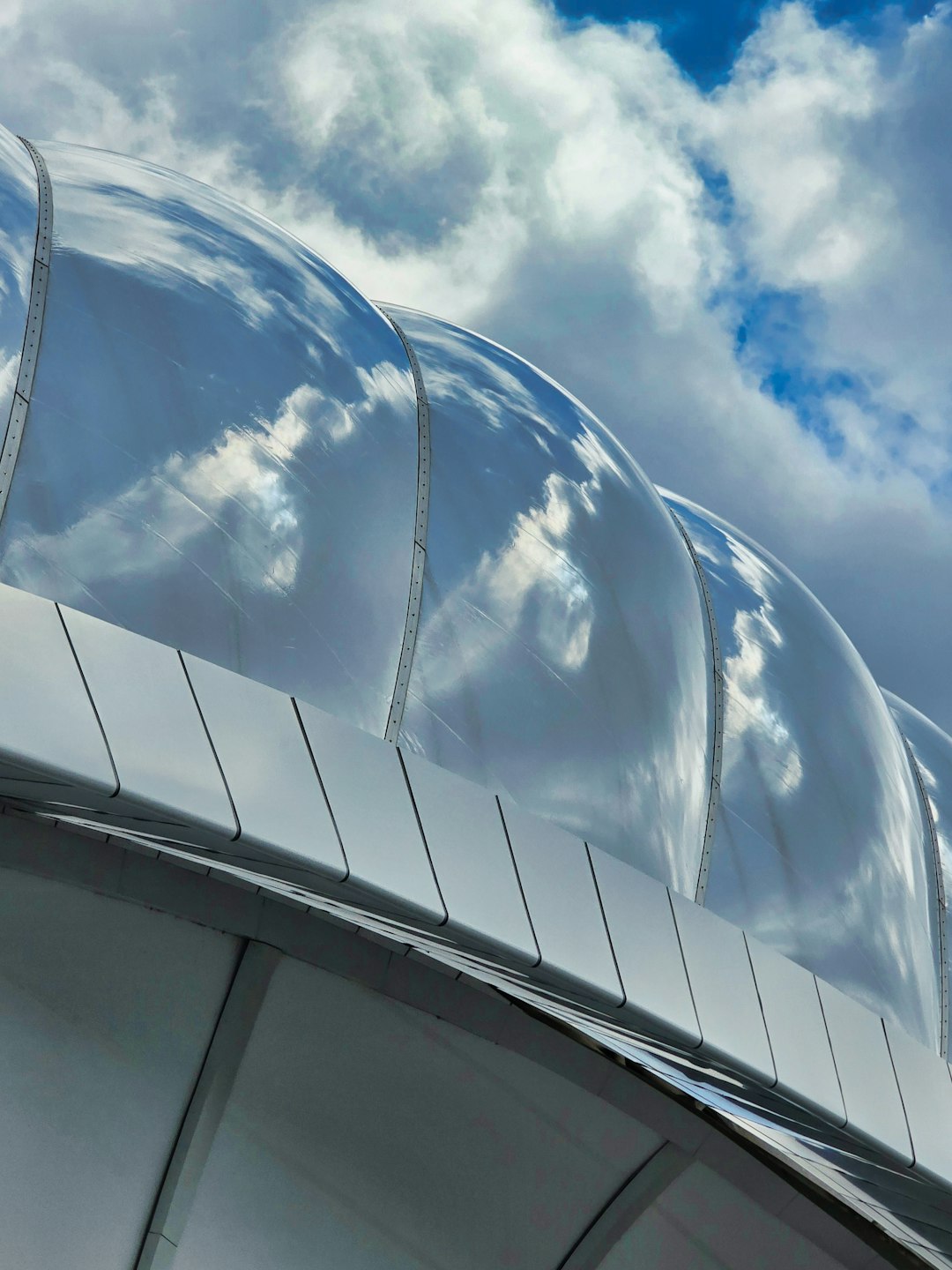 Modern building with reflective, curved roof against sky