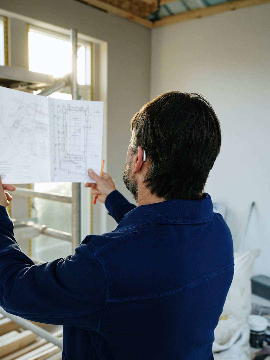 Blueprint Review at Construction Site Man reviews blueprints at construction site
