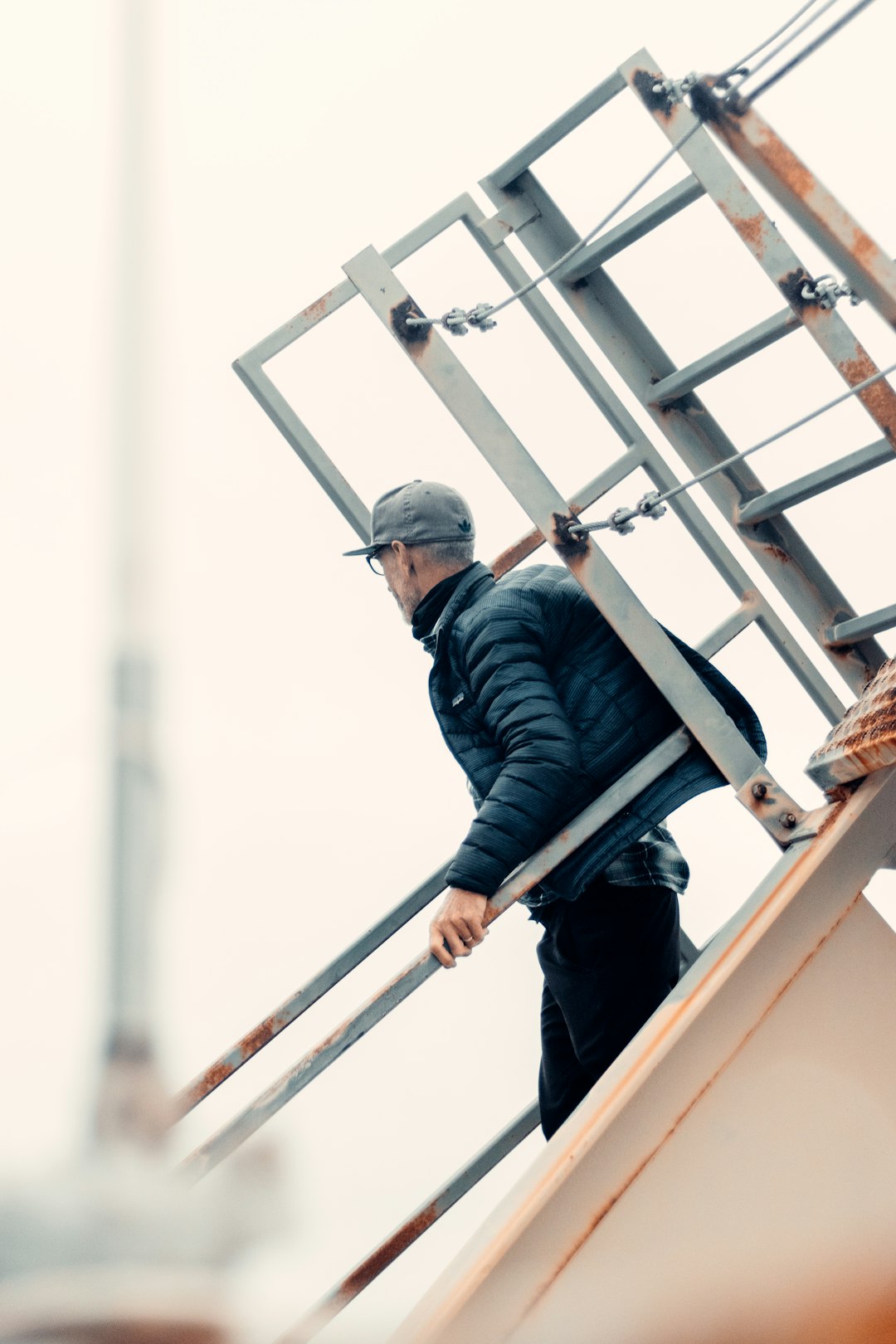a8602ccd0eb645a19d77d0b09f009045 man in black jacket and blue denim jeans standing on brown wooden ladder during daytime