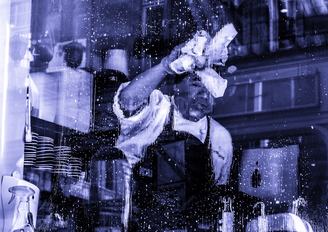 man in black apron wiping glass