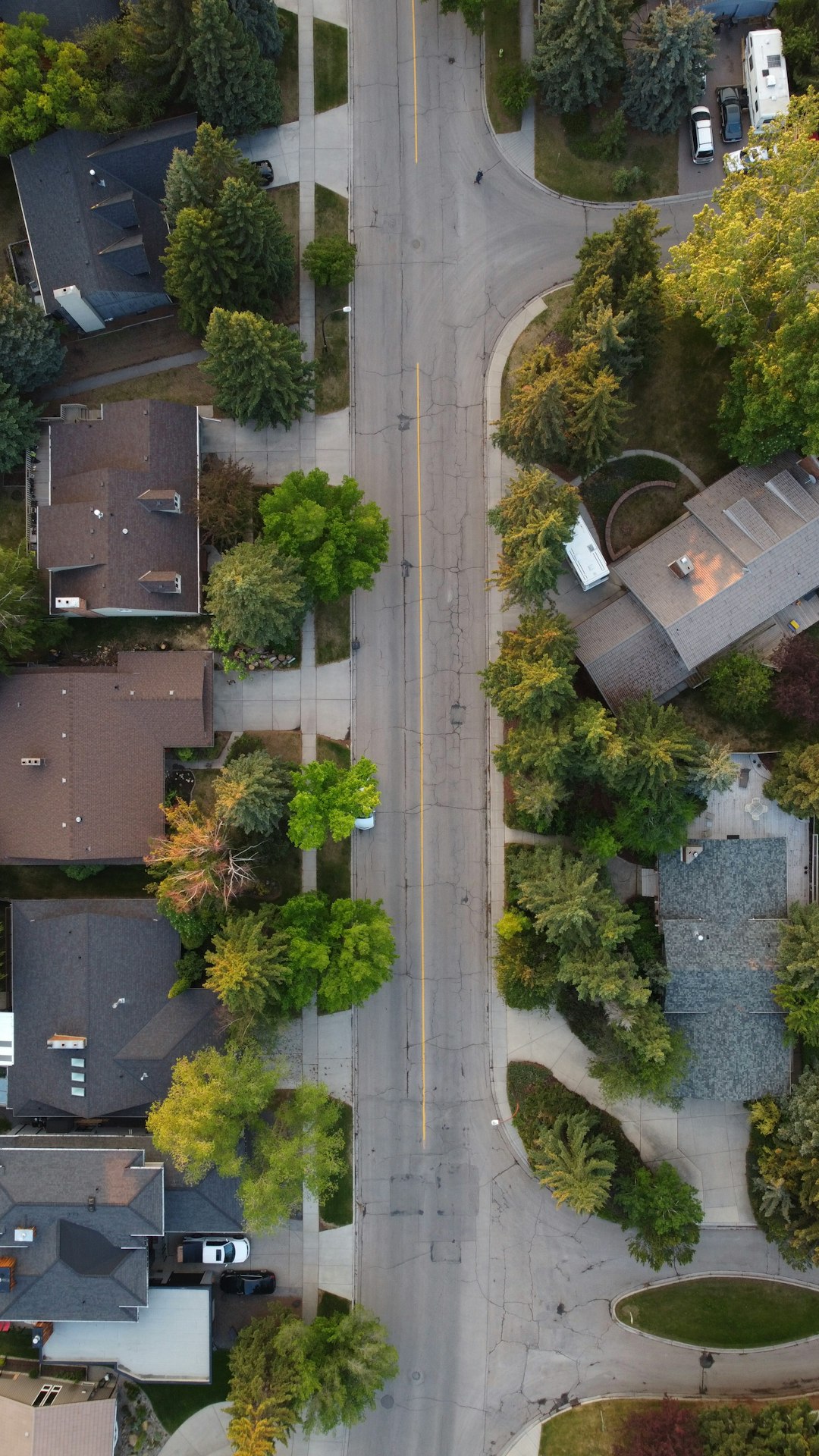 c06b5c054e4945d3aa2bf9ef54e41eb5 Aerial view of a suburban street with houses and trees.