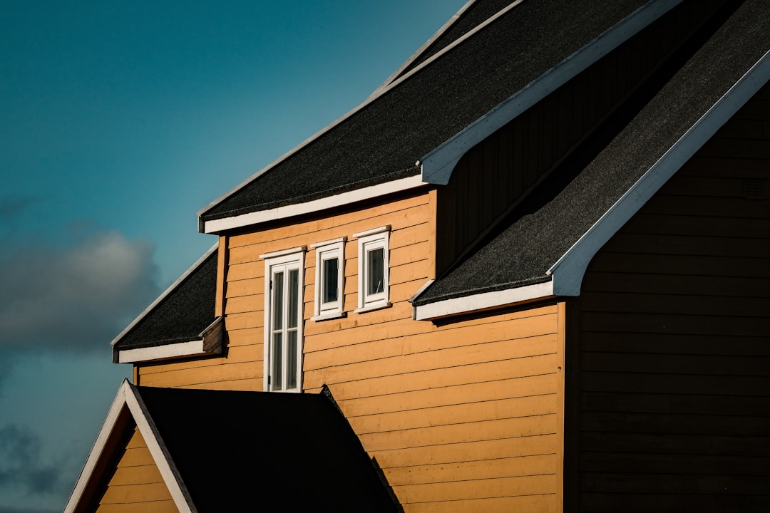 Wooden House with Shingled Roof A yellow house with black roofs.