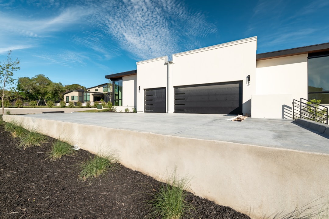 Modern house with two black garage doors under blue sky.