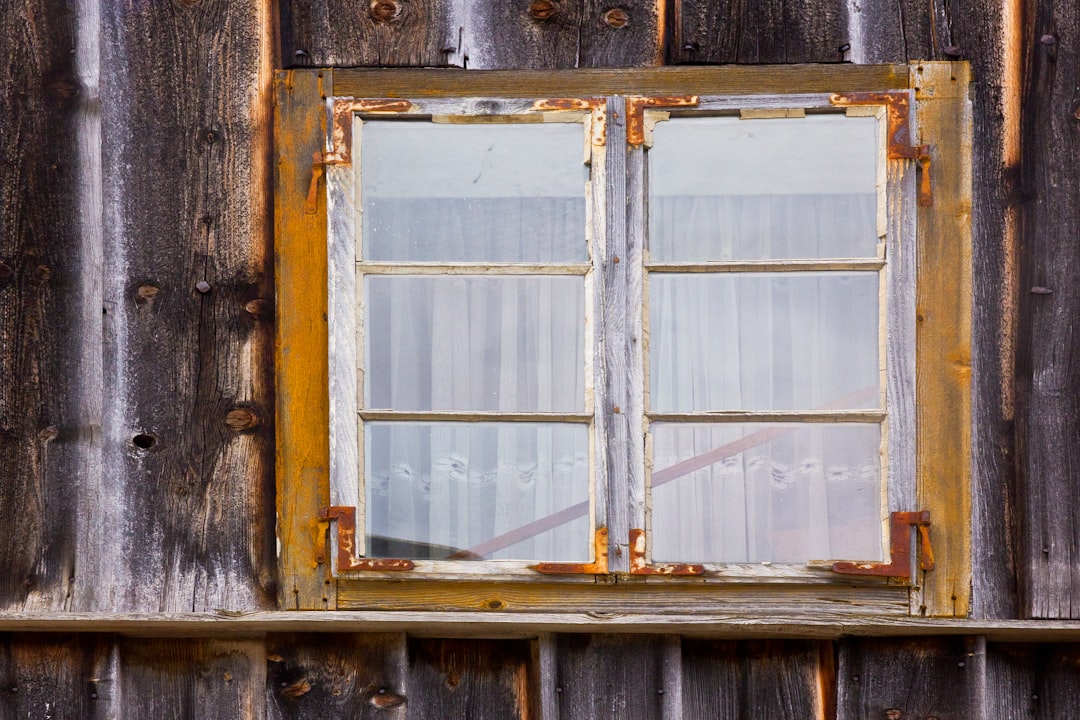 A weathered window sits in a wooden wall.
