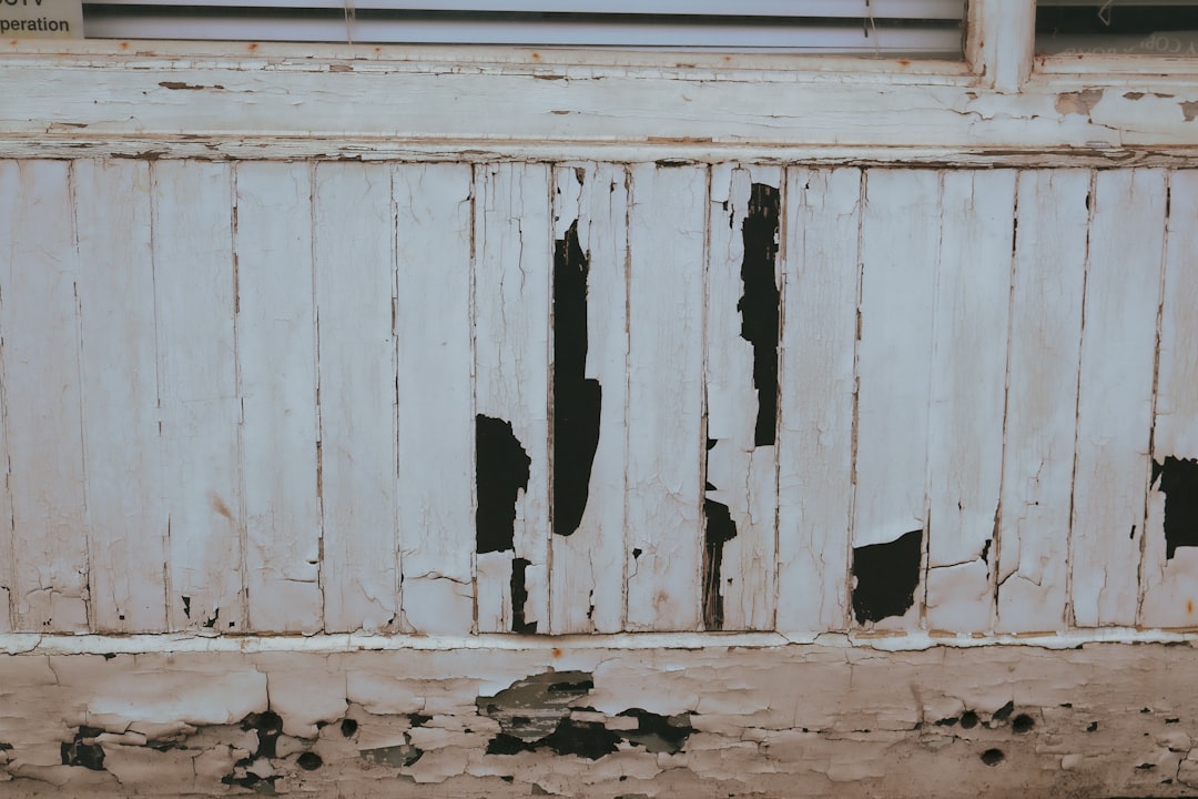 Peeling white paint on weathered wooden wall