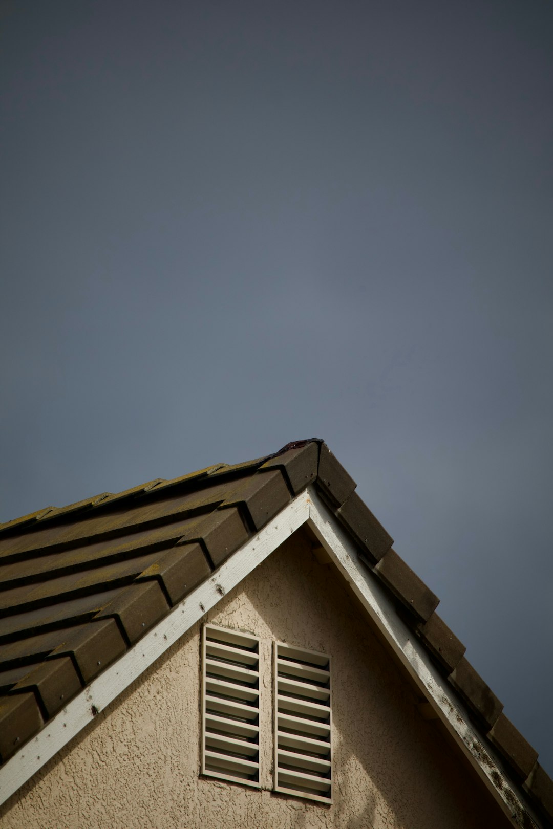 cc776741c1724dd5abccbaa240c8f11b House roof corner against a cloudy sky.