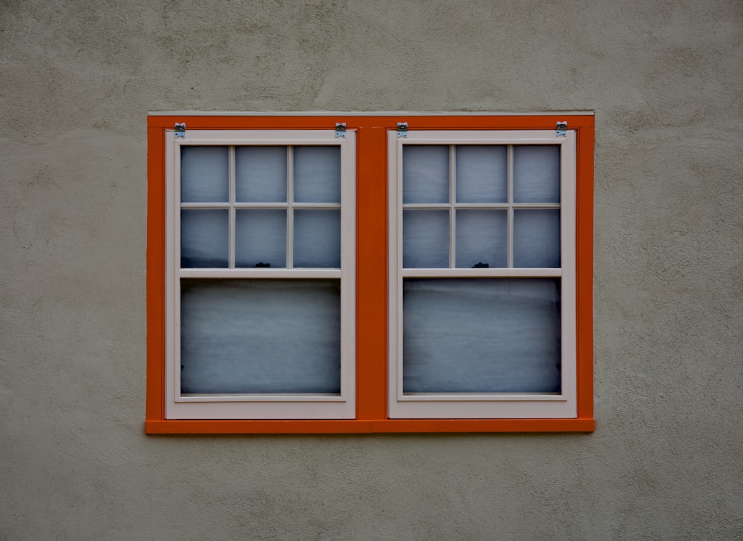 Two windows with orange frames on a grey wall