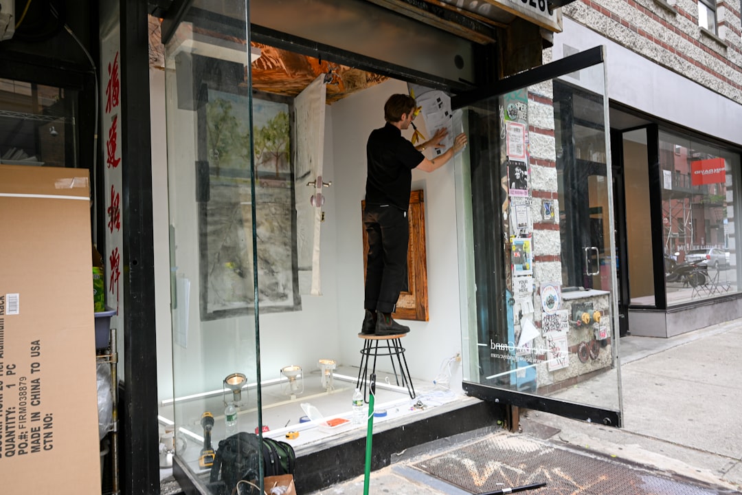 A person hangs art in a storefront window