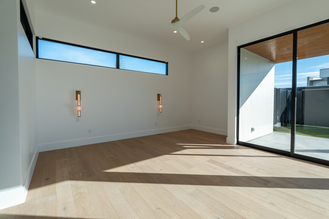 d8c526626ef04553992ec128cfec8bb4 Bright empty room with hardwood floors and large windows