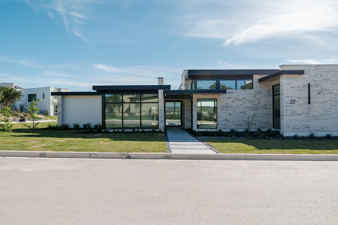 A modern house with large windows and a green lawn.