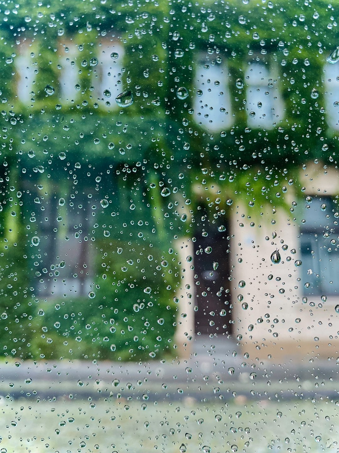 e18724688d794fa89e00d390e39cbe17 rain drops on a window with a house in the background