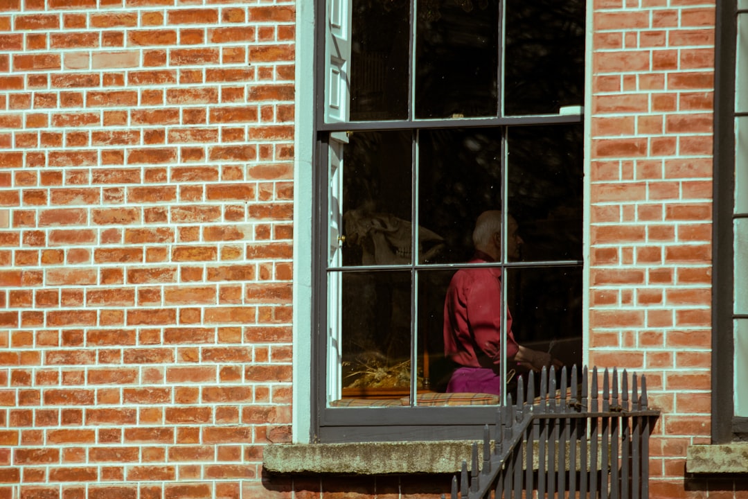 Person in red seen through a brick building window.