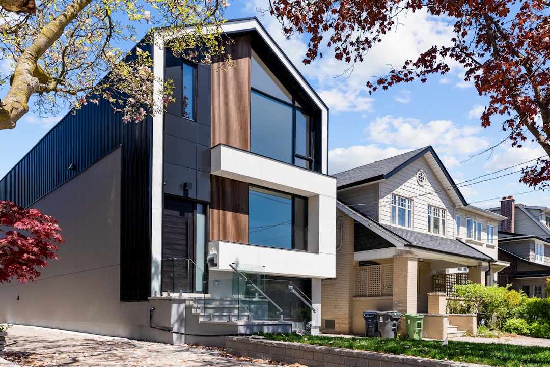 e6ecf56ce85f47529aa13a8dc452c0f0 A modern house with black metal siding beside a traditional beige house
