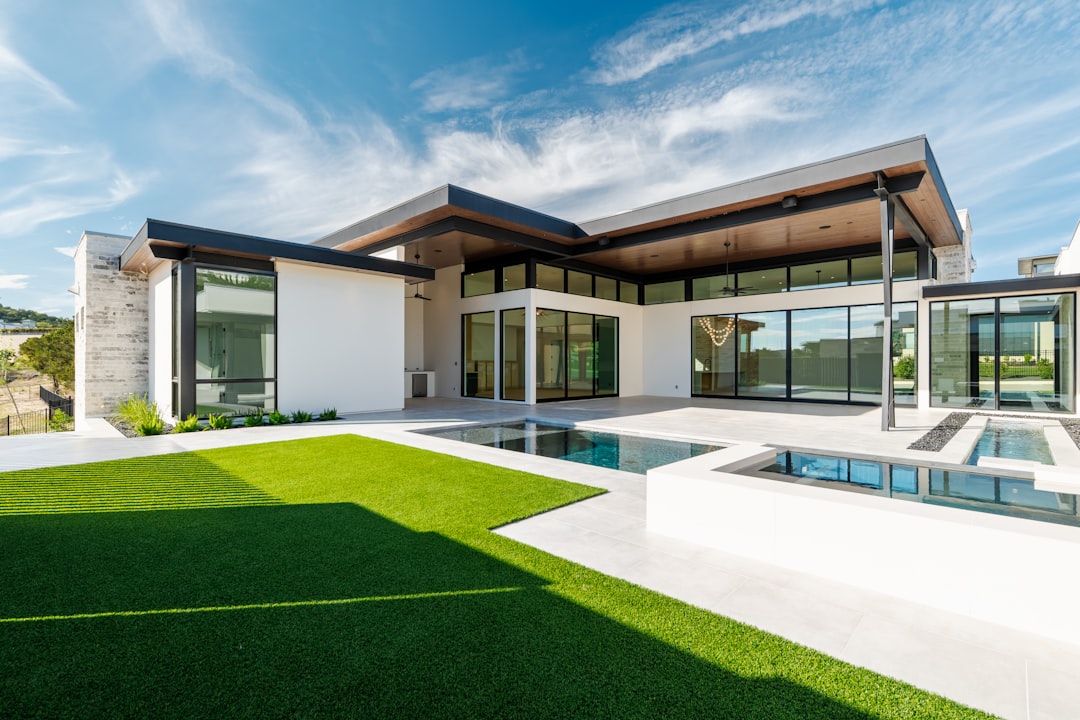 e902753917c64b548cc2b415553e8789 Contemporary house with swimming pool and lush green lawn.