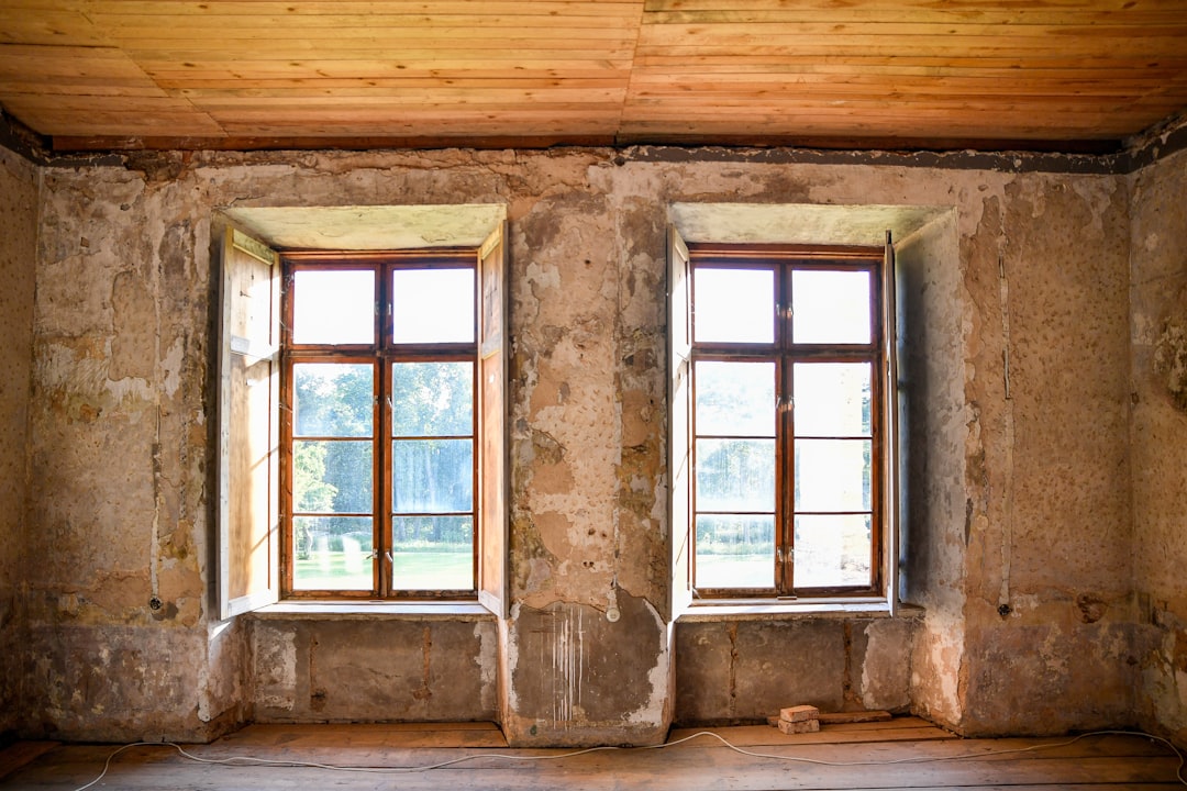An empty old room with two windows and distressed walls