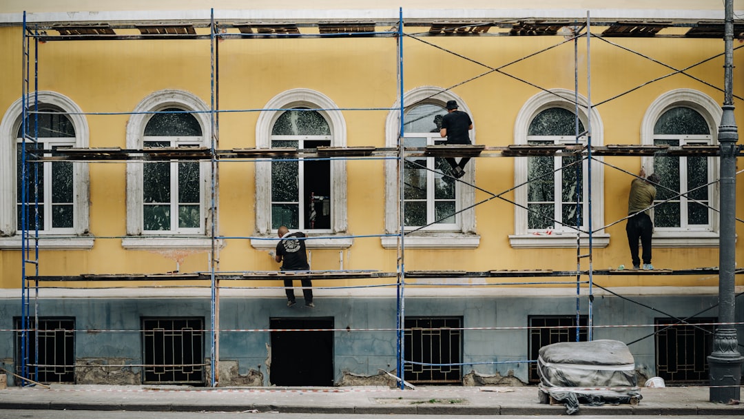 Workers on scaffolding repairing a yellow building facade