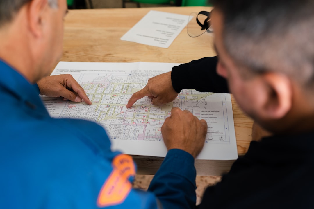 Two people in blue uniforms pointing at a printed map on a table