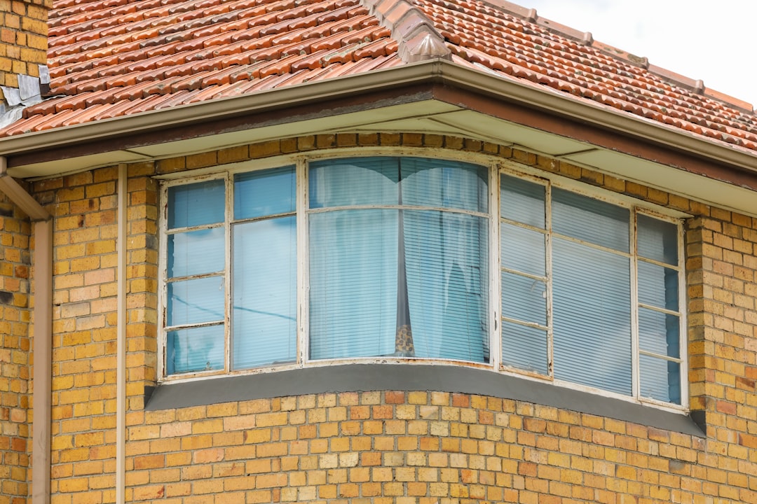 eb5a4d88186e42c1b6ce7a0c9827d8eb close-up photo of brown concrete house with glass windows during daytime