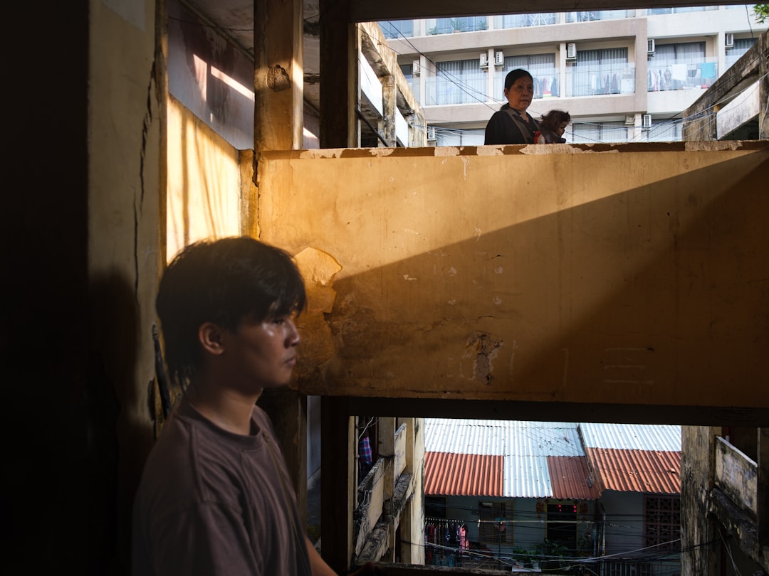 ec70066b00c54b958d036ec164928d29 A person looks out a window with another person above