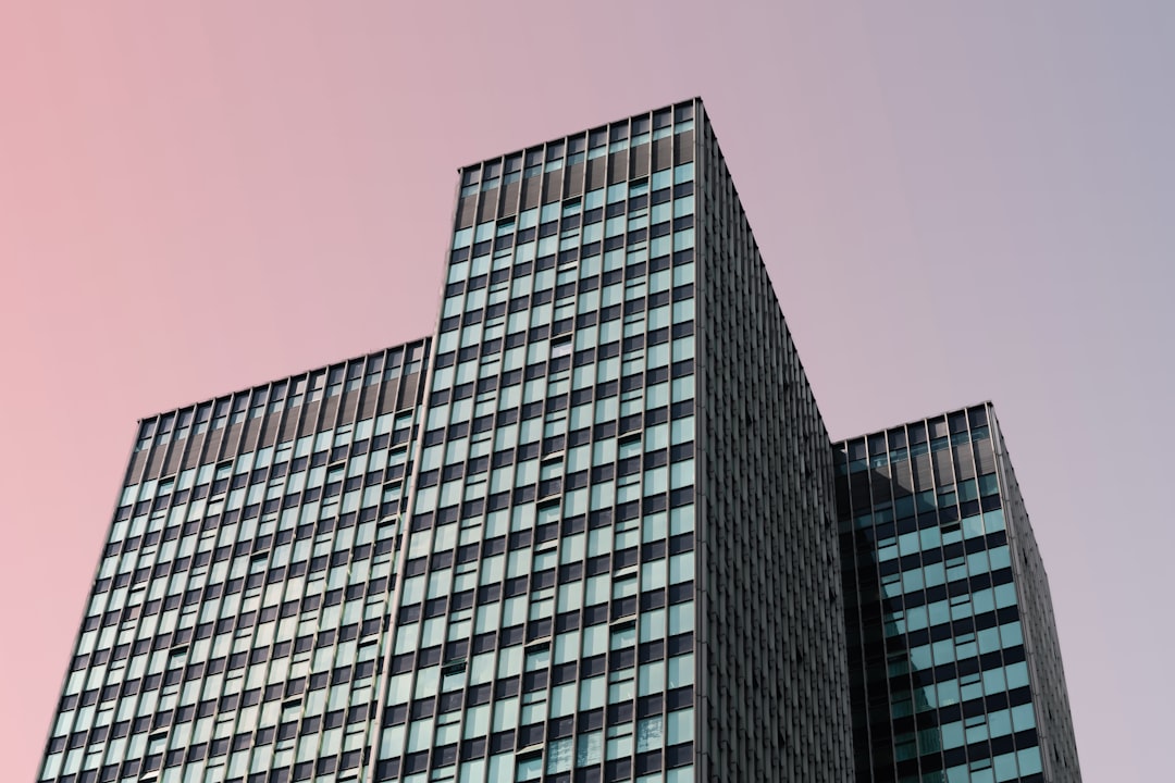 Angular multi-wing office building with blue-tinted windows against a pastel sky