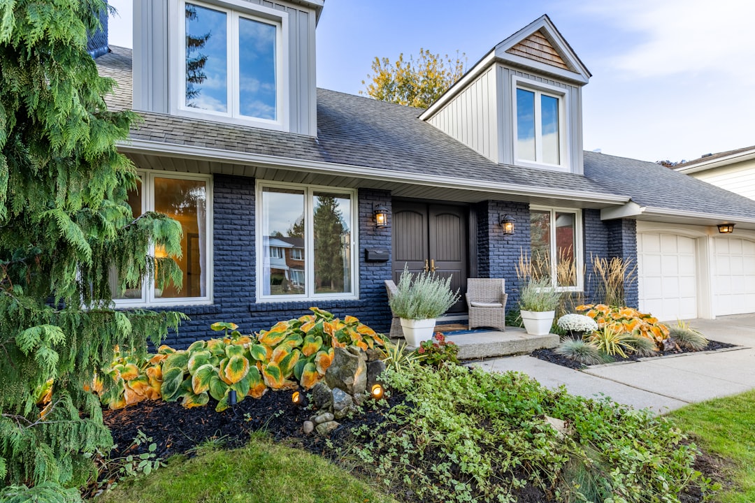 f4265c91ddc7488ca922f3baa9827b54 A house with dark blue brick siding and a front garden with hostas