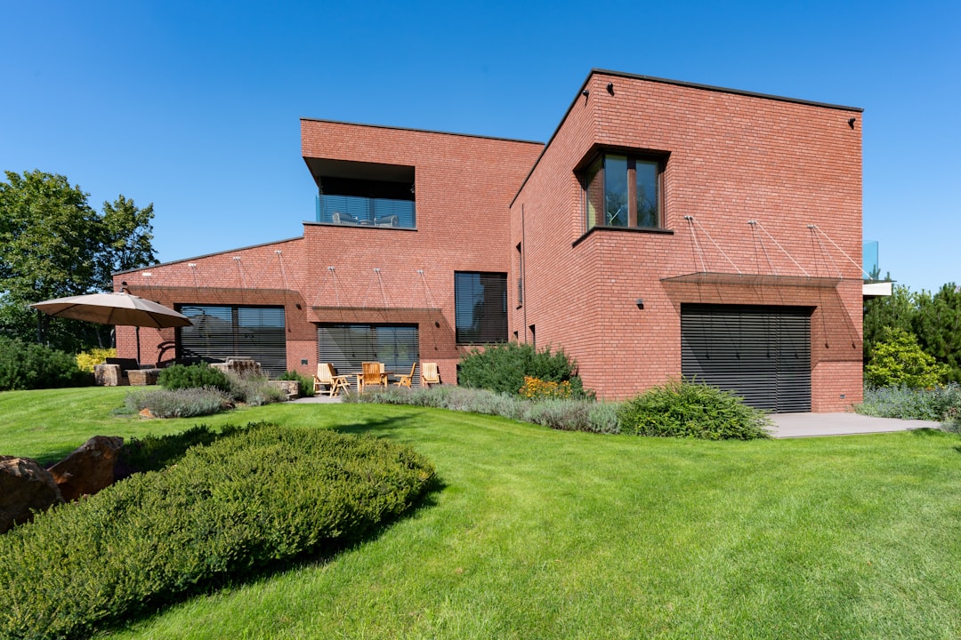 f6a6283d59d546d9ae3d1e5c3b511cec a large brick house with a green lawn in front of it