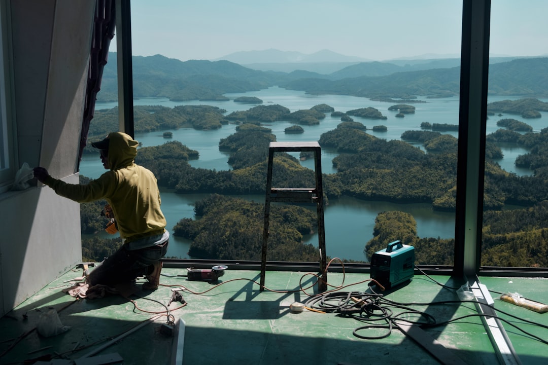 Worker Preparing Tools Inside Room man in green shirt sitting on the edge of a building looking at the lake during