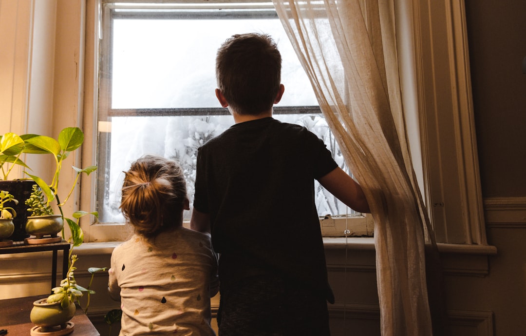 fad3d21b931e4e2197fbd30f15ea8981 boy and girl standing near window looking outside