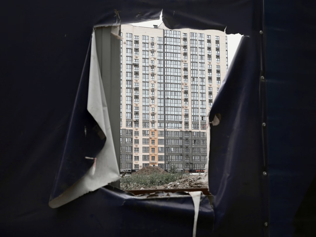 Tall apartment building seen through torn fabric.