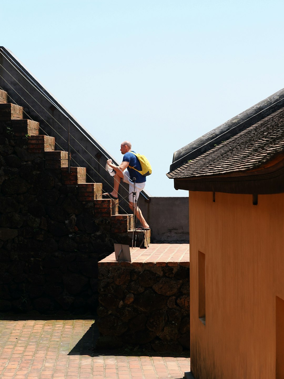 Man with yellow backpack climbs outdoor stairs