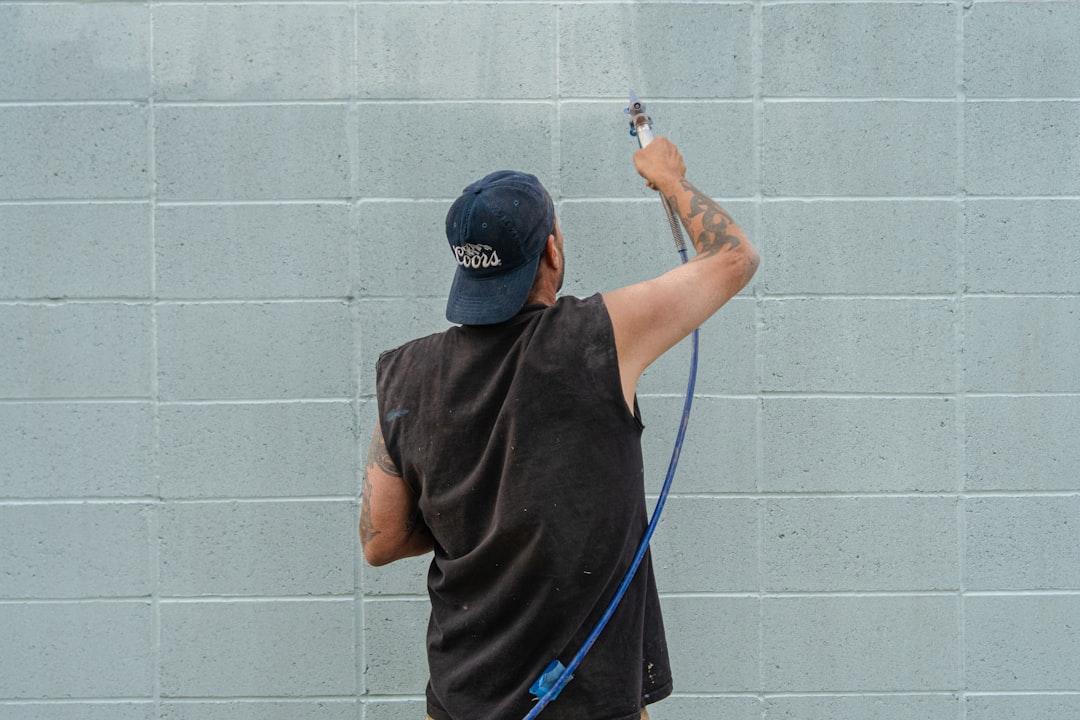 A man is painting a wall with a sprayer