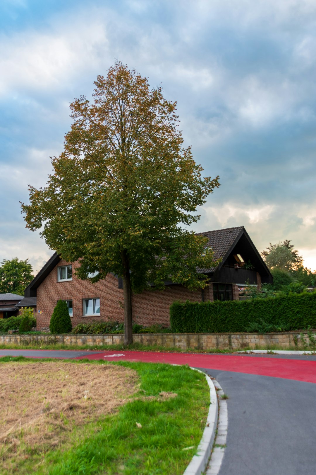 Brick house with a large tree and red path