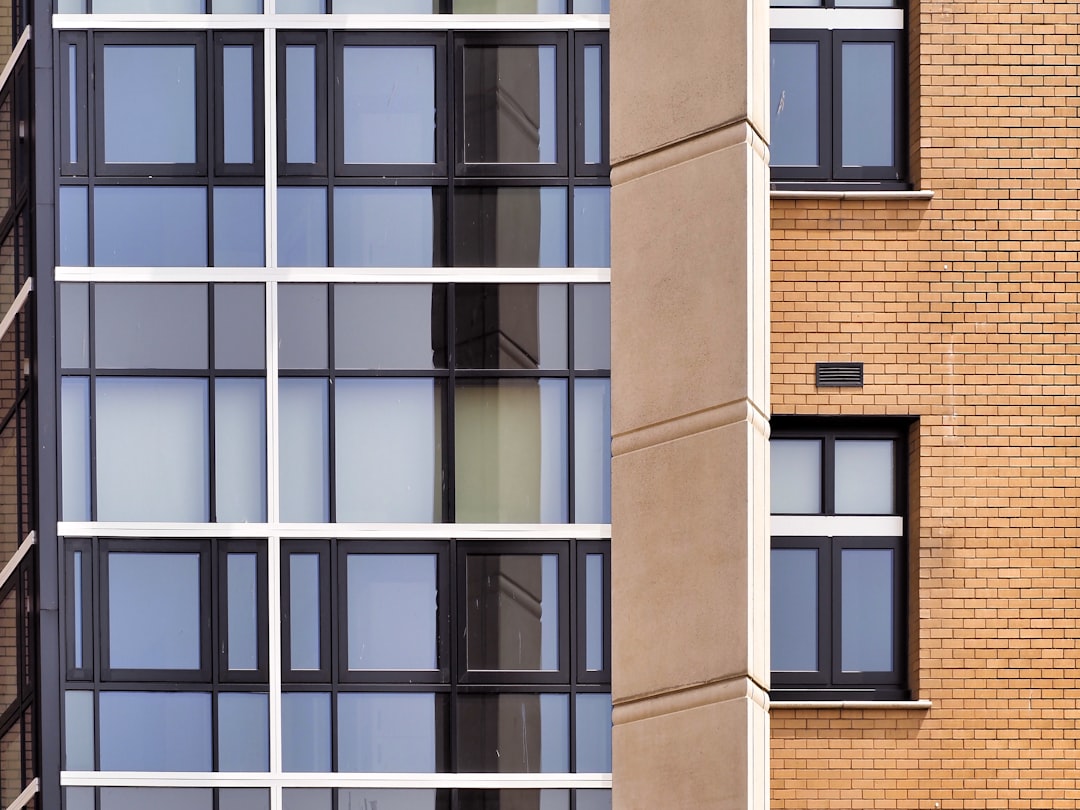 A modern building facade with glass windows and a tan brick wall section