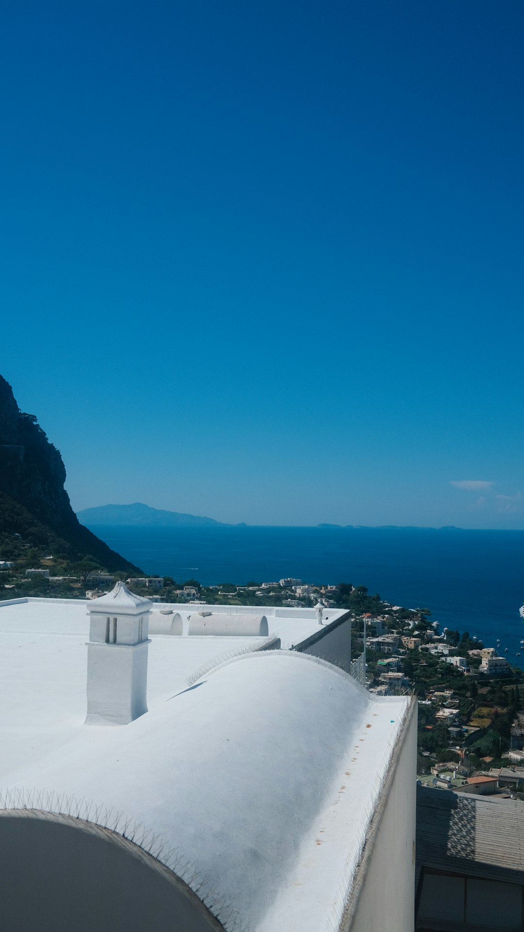 White rooftops overlook a coastal town and blue ocean