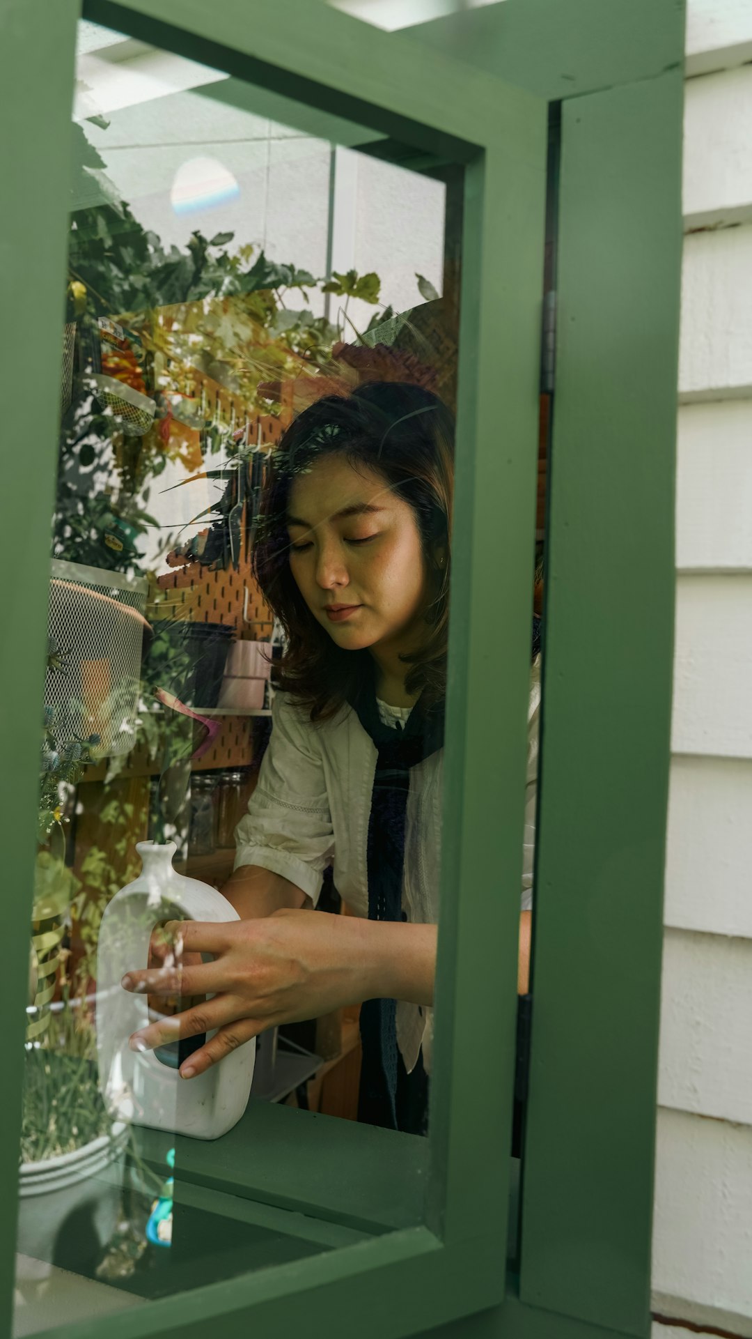 Woman arranging items through a green window frame