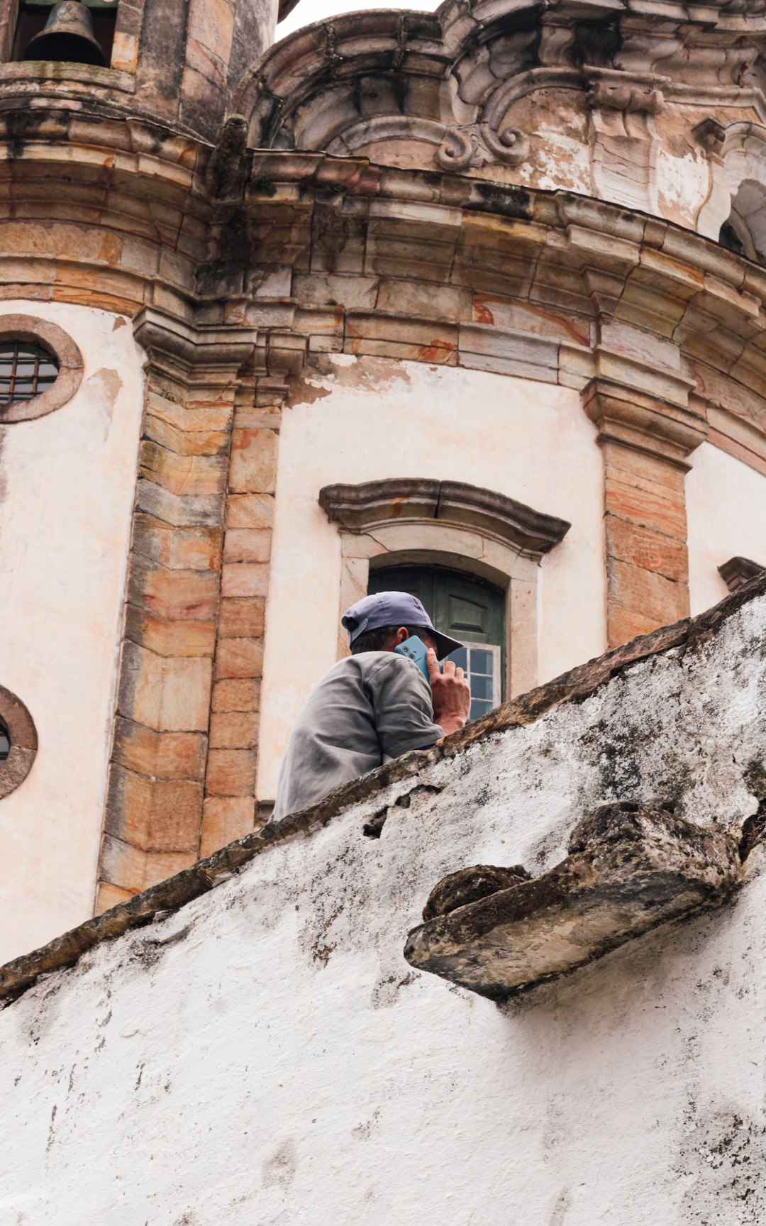 6a6e6911c1ae4b42881e6a5afebc56d3 Person wearing a hat and mask looks at building