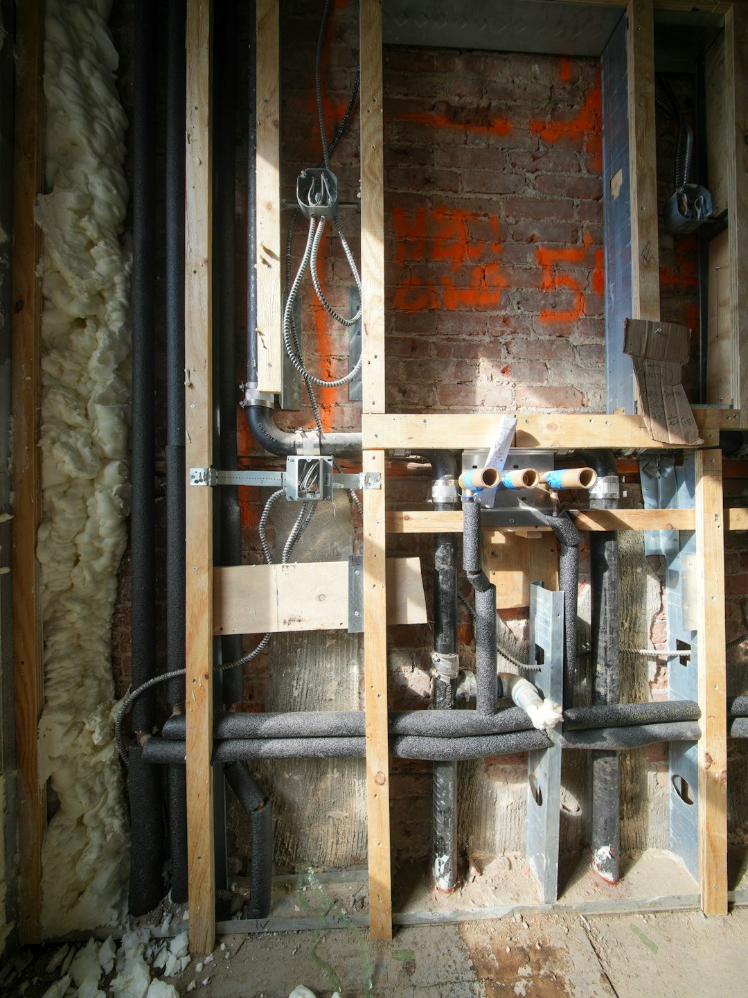 Exposed plumbing and wiring within wooden wall studs