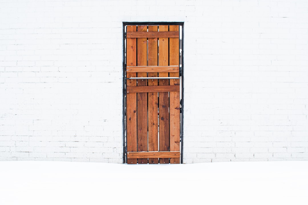 7022b518c54a4d6583d9e82360ab6128 an open wooden door on a white brick wall
