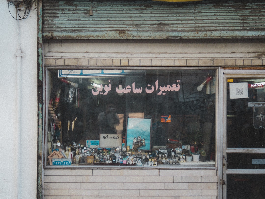 7bed111d617840bface1a65976eb4905 Grungy storefront window with arabic writing and cluttered items inside