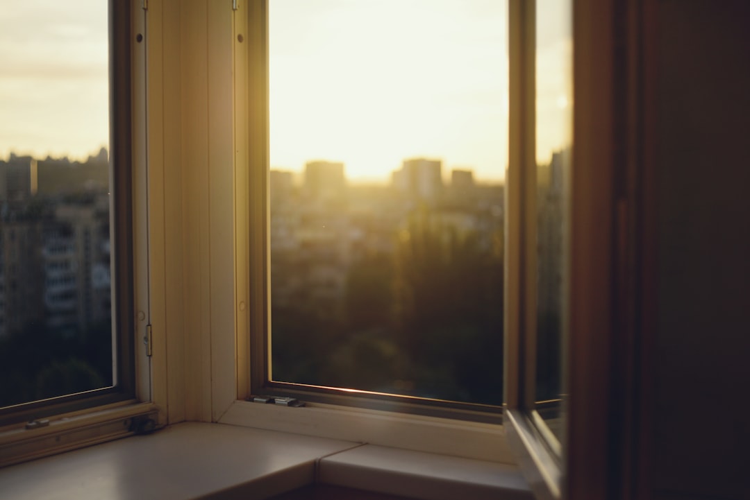 8673da3f8a6f4e81b7bc98ff8a3411dd City skyline at sunset viewed through a window