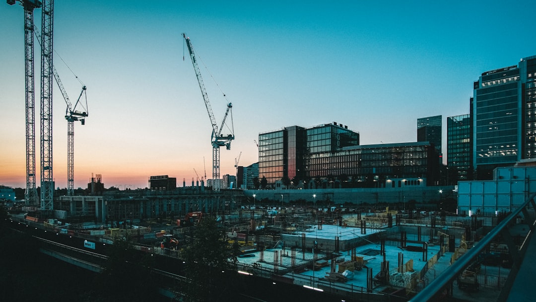 Construction cranes over a building site with concrete foundations at low sun