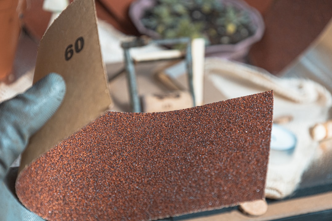 998abf345d1144229f5fafbcc843f6a3 Hand holding sandpaper with grit number 60