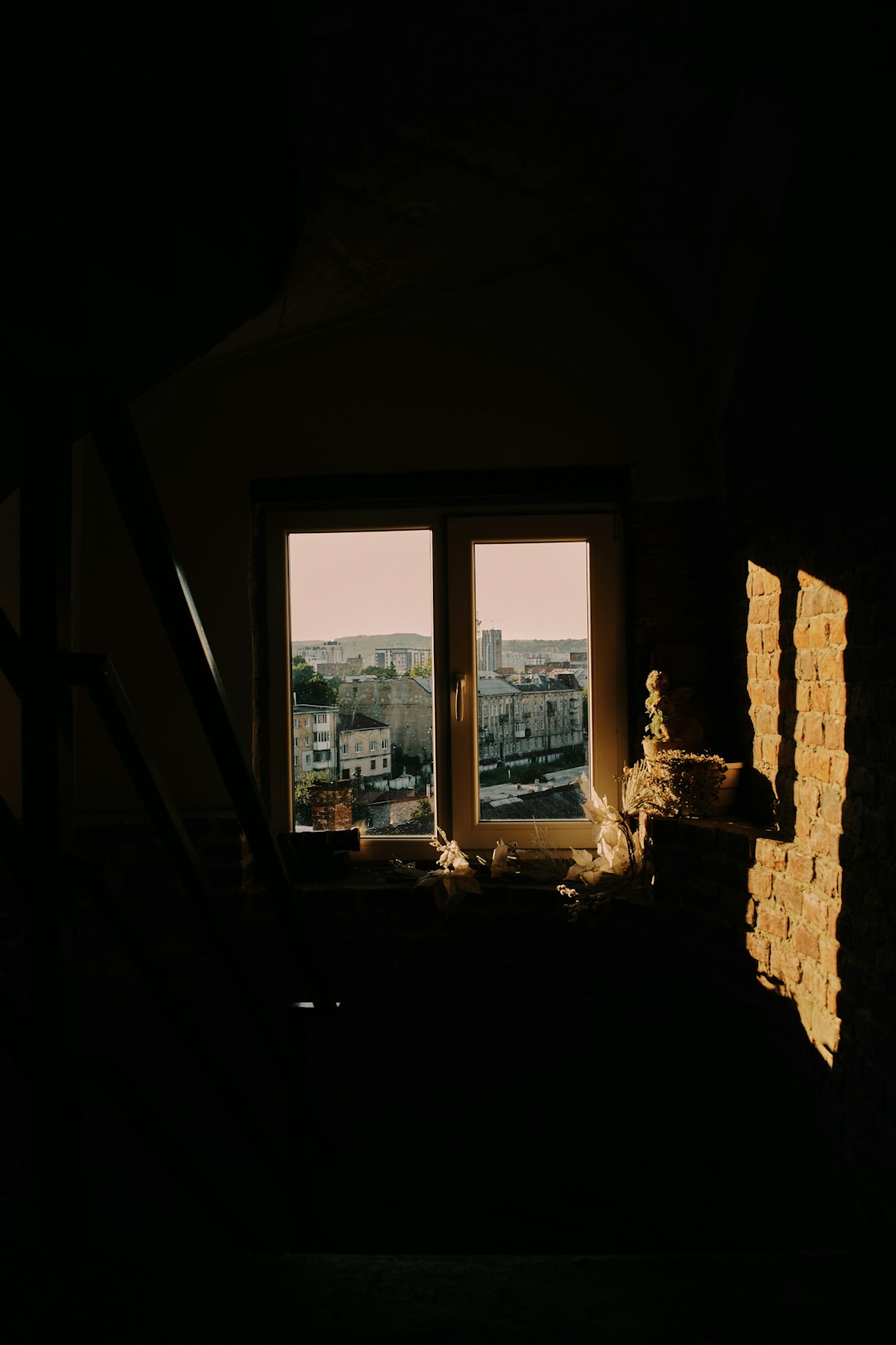 A window in a dark room with a view of a city