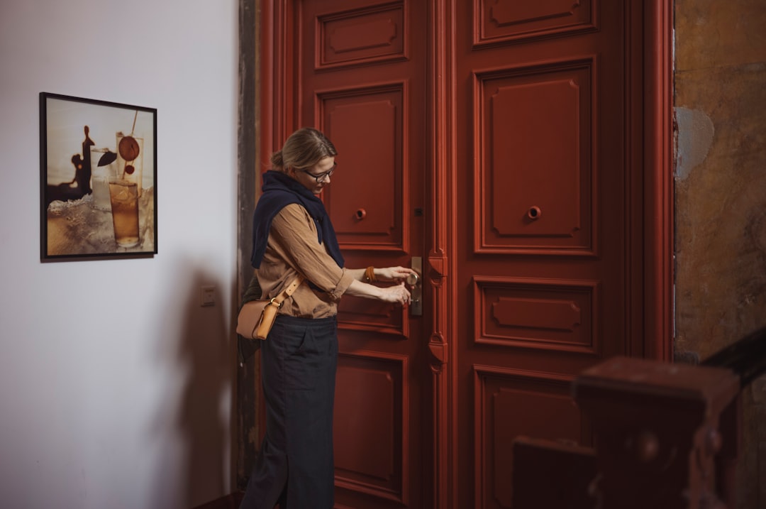 Woman opening a large red wooden door