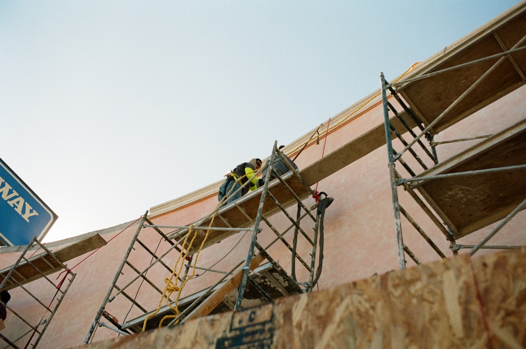 b15841553ccd41029d2d930dfac579b3 man in yellow shirt climbing on brown concrete building during daytime
