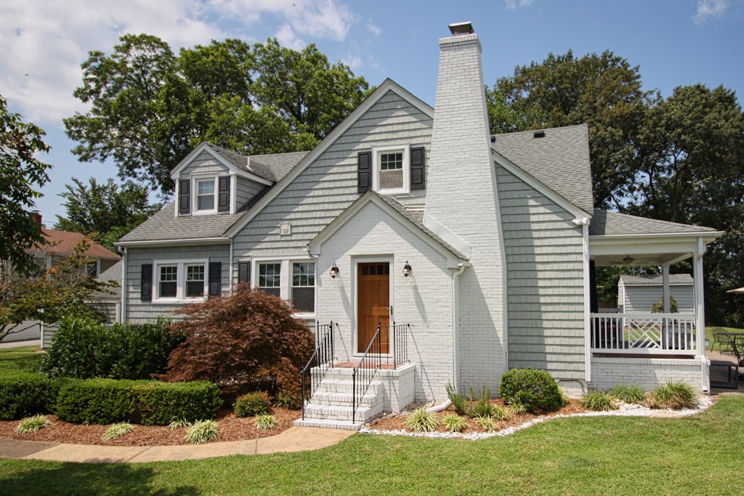 be4241259f094cb483944bde14bf7fbe a gray house with a white porch and a brown door