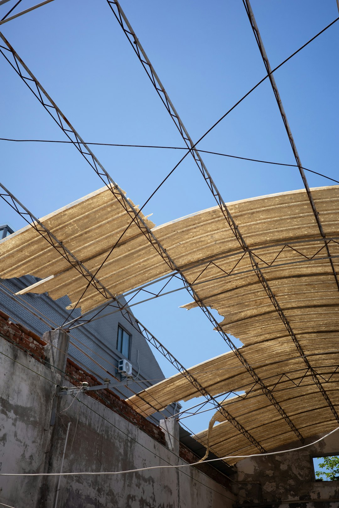c5df34fb1d97437897fa3c46fb231acf A torn canvas canopy over a building under blue sky