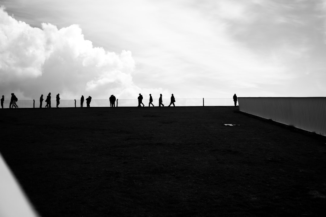 Silhouettes of people walking on a rooftop under clouds
